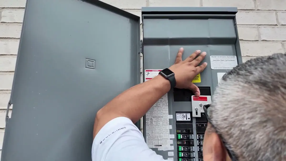 Hand sliding the interlock plate on an outdoor breaker panel