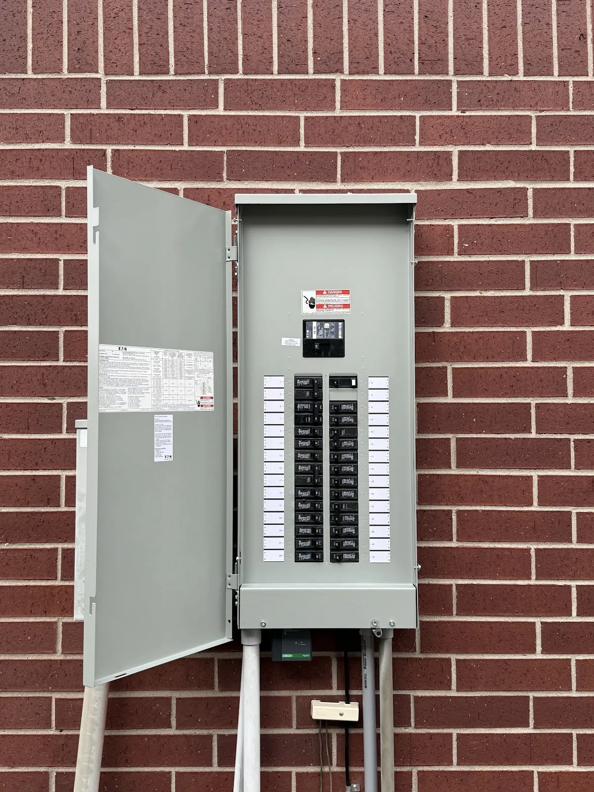 New gray breaker panel mounted on a red brick wall, installed by Pro Max Electrical