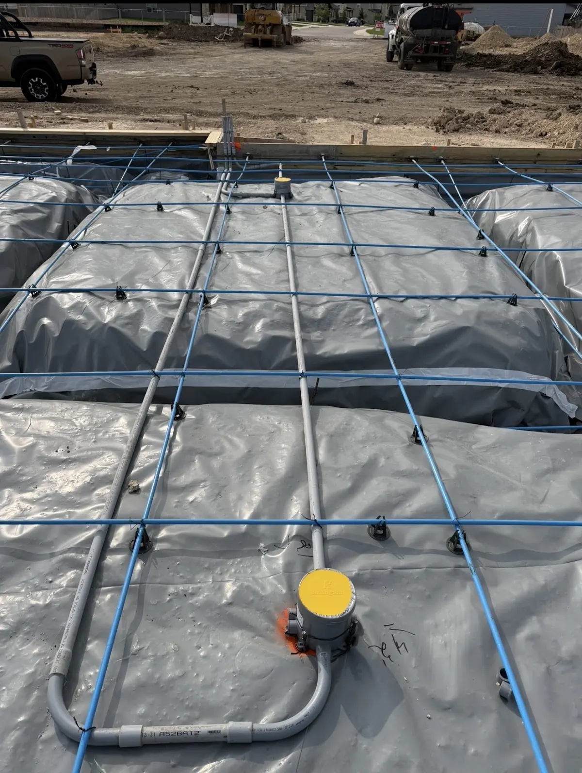Blue electrical conduit laid out on plastic sheeting before a concrete slab pour, by Pro Max Electrical