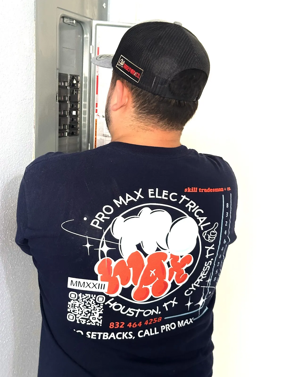 Pro Max Electrical technician in the company shirt working at a breaker panel